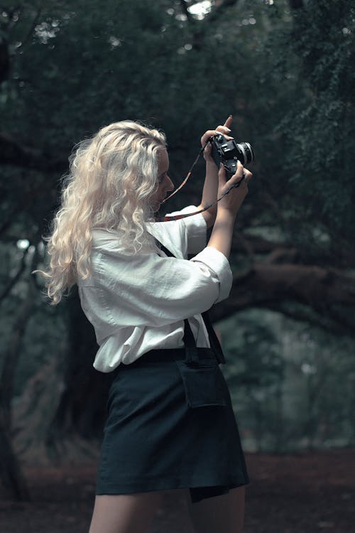 Free A Woman in White Long Sleeve Shirt Holding a Camera Stock Photo