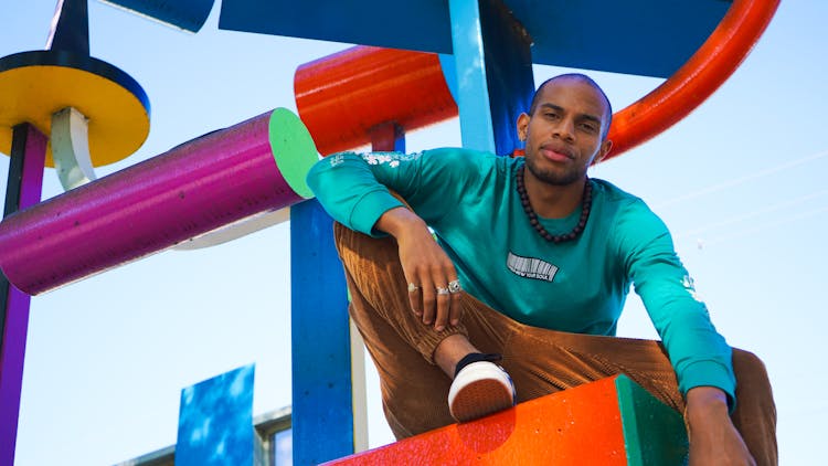 Man In Green Sweatshirt Sitting In Playground