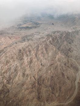 Dramatic aerial view of rugged mountains covered in mist, showcasing natural formations.