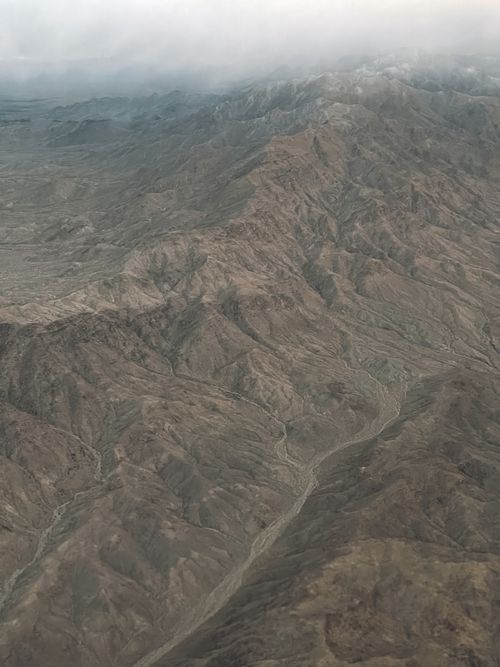 Free A captivating aerial view showcasing expansive mountain ranges shrouded in a misty atmosphere. Stock Photo
