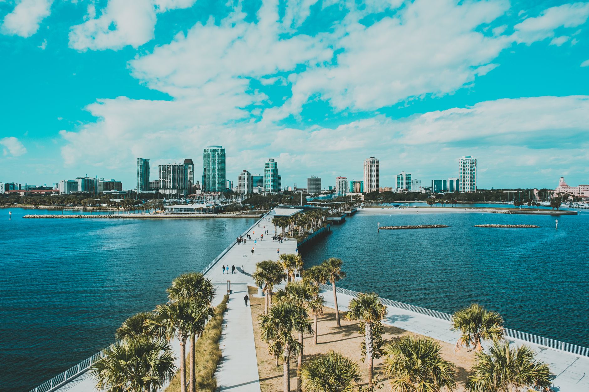 Enjoy a stunning aerial view of a Florida coastal city with palm trees, pier, and clear skies.