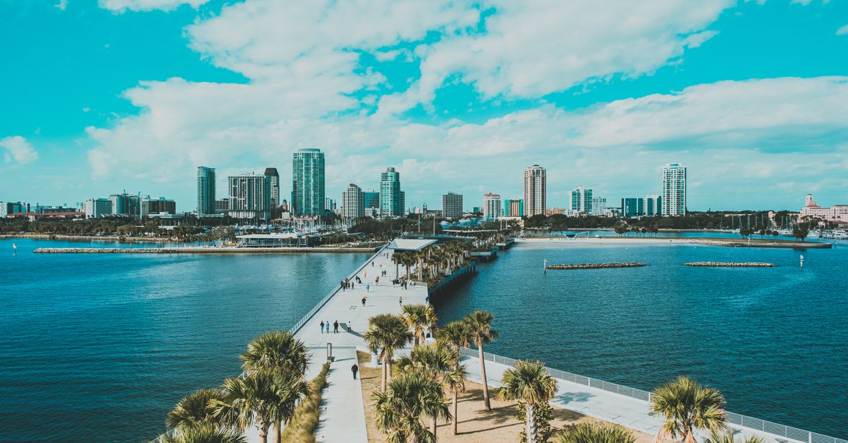 Enjoy a stunning aerial view of a Florida coastal city with palm trees, pier, and clear skies.