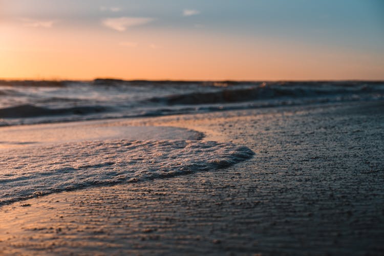 Waves Crashing Onto Shore At Sunset