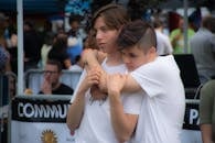 在一场热闹的户外社区聚会上，两名青少年深情相拥