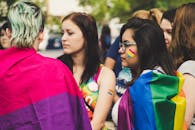 一群妇女裹着彩色旗帜，在户外骄傲活动中庆祝多样性