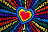 心形设计色彩缤纷，采用彩虹渐变，并在黑色背景上点缀着小心形辐射图案