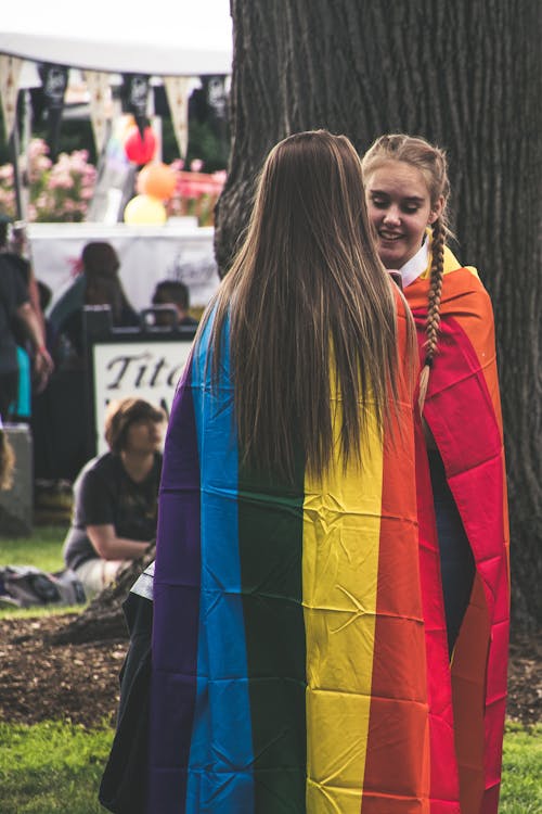 Photo of Two Woman Wearing Rainbow Capes