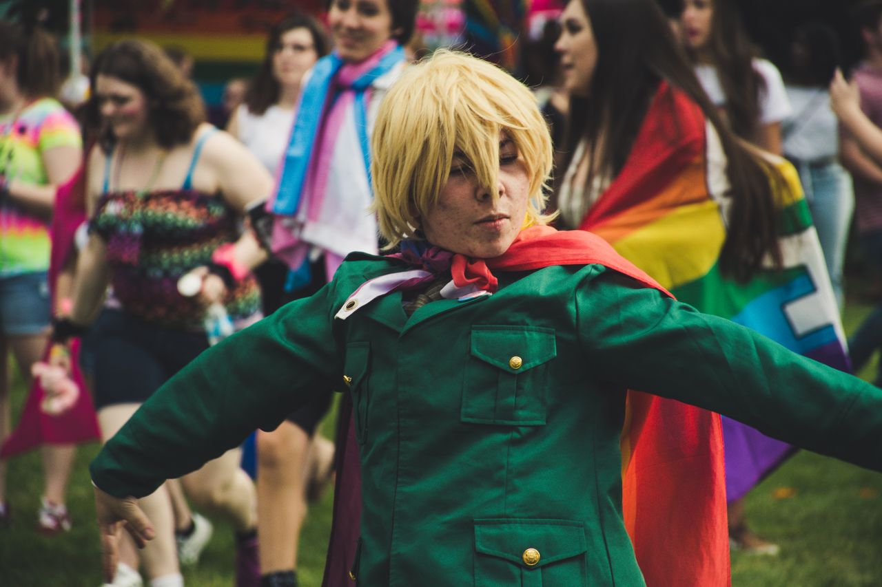 a lively pride event with people celebrating in colorful outfits and f
