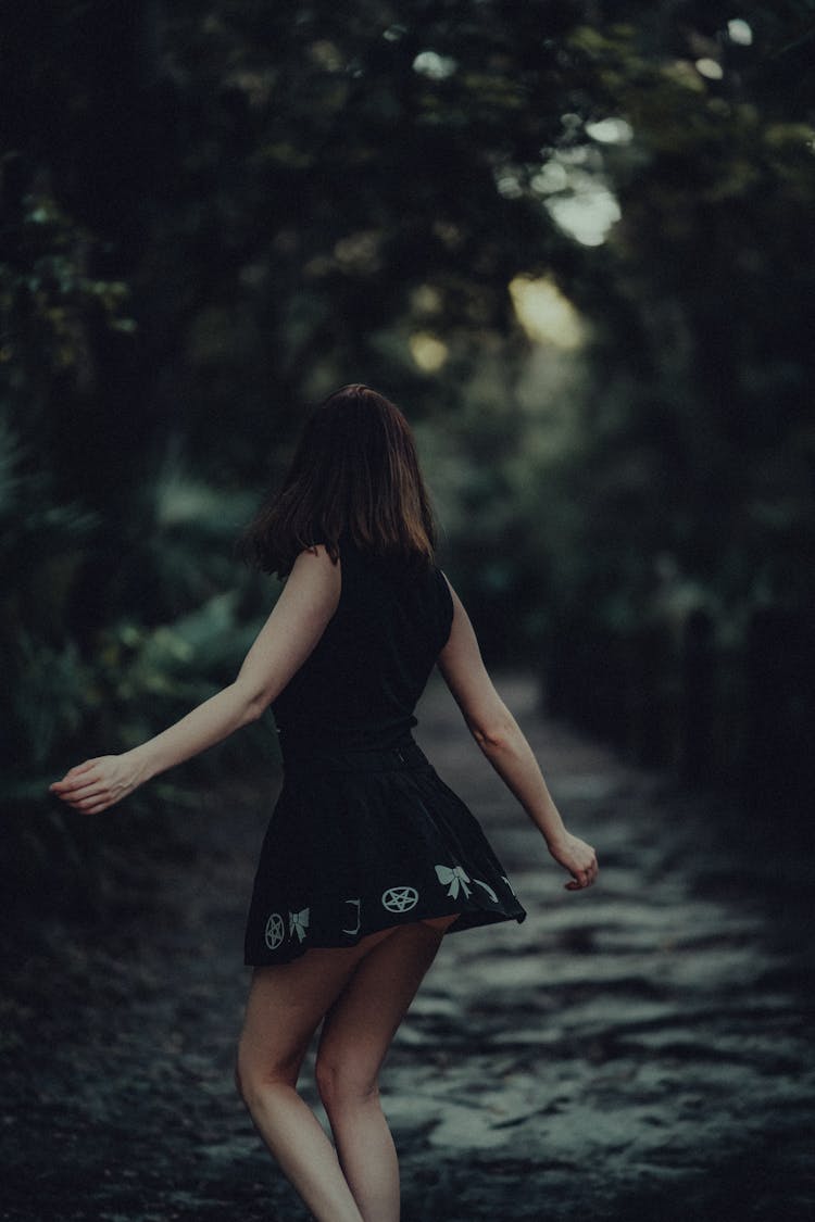 Woman In Short Black Dress Dancing In Dark Forest