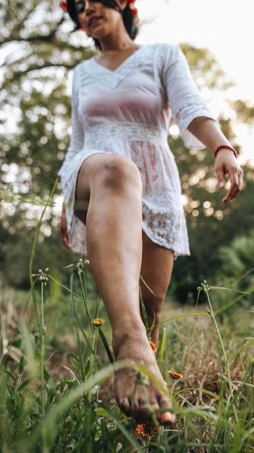 Woman in White Dress Walking Barefoot across Meadow