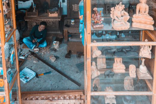 Skilled craftsman working on wooden sculptures in a rustic workshop setting.