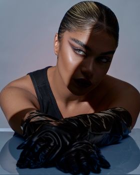 Moody portrait of a stylish woman with dramatic shadows and elegant gloves.