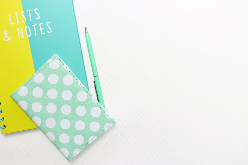 Flatlay of a polka dot wallet, pen, and notebook with copyspace on a white background.
