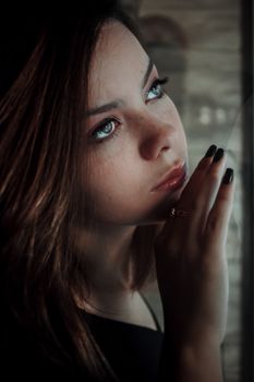A contemplative woman gazes out a window, capturing a moment of introspection.