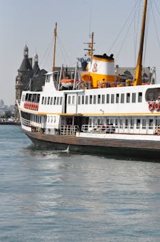 A passenger ferry sails on the Bosphorus with a historic Istanbul building in the background.