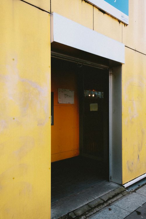 Free Stylish urban building entrance with vibrant yellow exterior and open doorway. Stock Photo