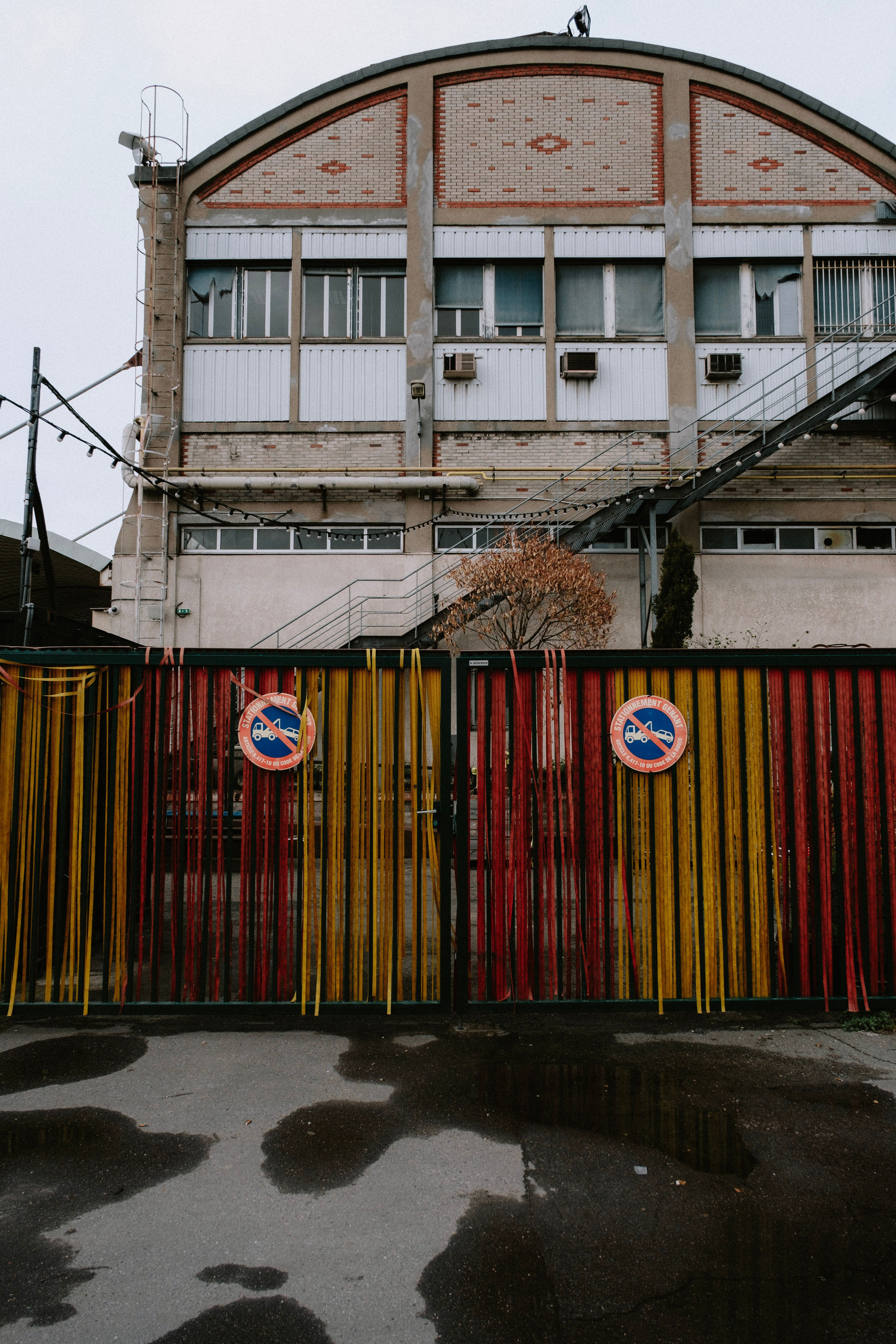 Exterior view of an old industrial building with a vibrant striped gate surrounding the entrance.