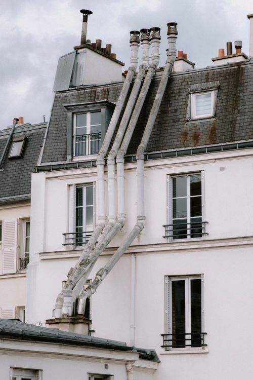 Free Detailed view of rooftop architecture with multiple chimneys in an urban city setting. Stock Photo