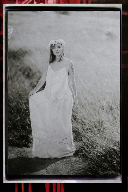 Elegant black and white portrait of a woman in a white dress, with vintage aesthetics and floral headpiece in a natural setting.