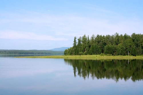 Free Peaceful lake scene with forest reflection in Bratsk, Russia, under a clear sky. Stock Photo