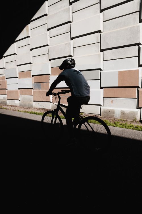 Free A silhouette of a cyclist wearing a helmet, riding through a tunnel in an urban setting. Stock Photo