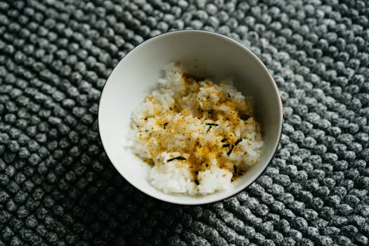 Close-up of Japanese rice bowl topped with furikake, a traditional seasoning, on a textured surface.