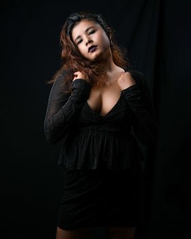Elegant portrait of a fashionable Asian woman posing in a black studio setting.