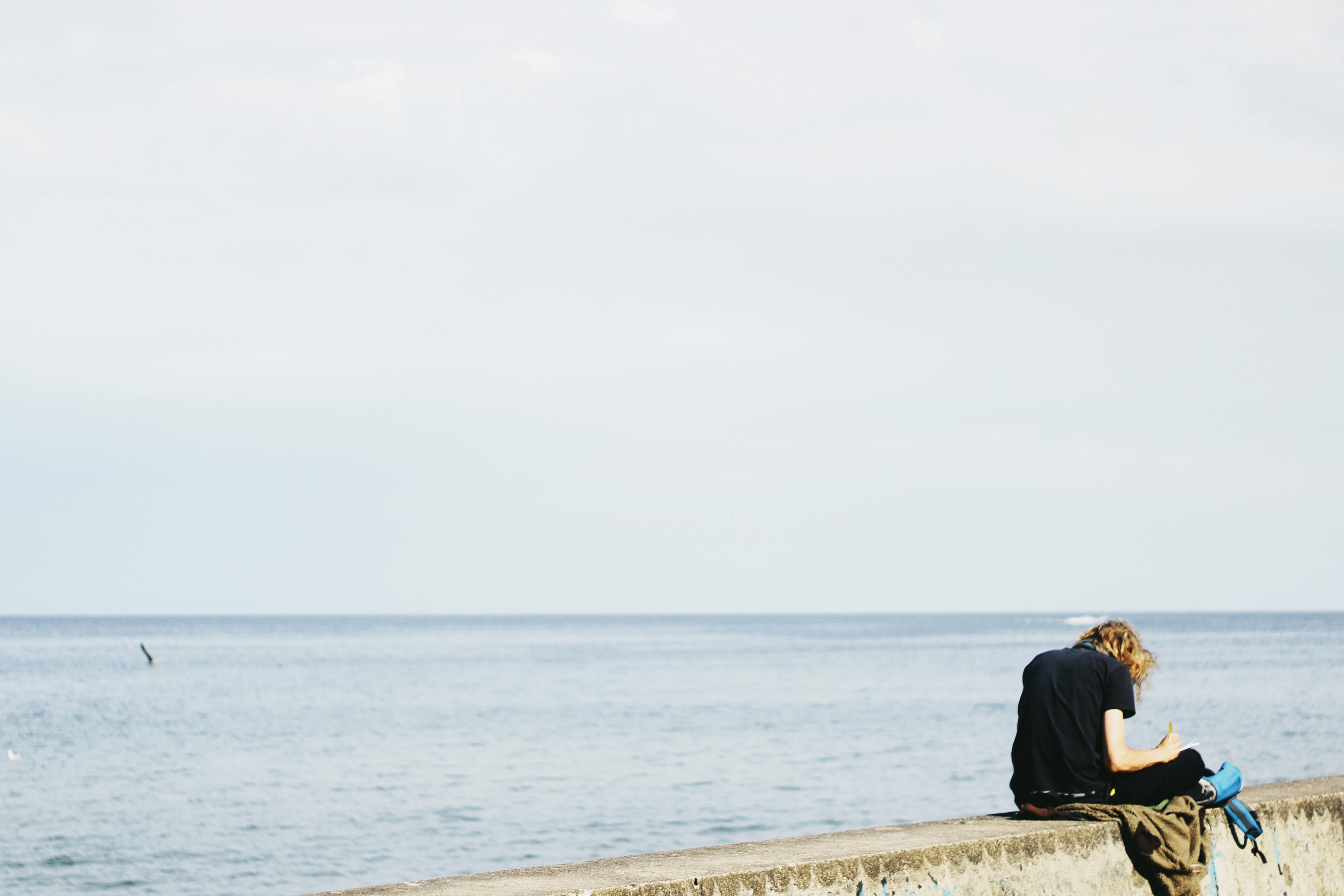 無料 灰色の表面に座っている黒いシャツを着ている人 写真素材