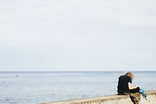 Person Wearing Black Shirt Sitting on Gray Surface