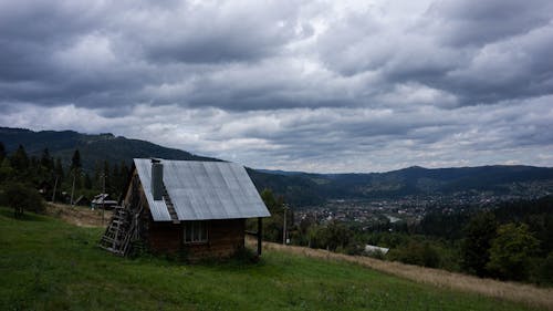 A Wooden House on a Grass Field Under Cloudy Sky