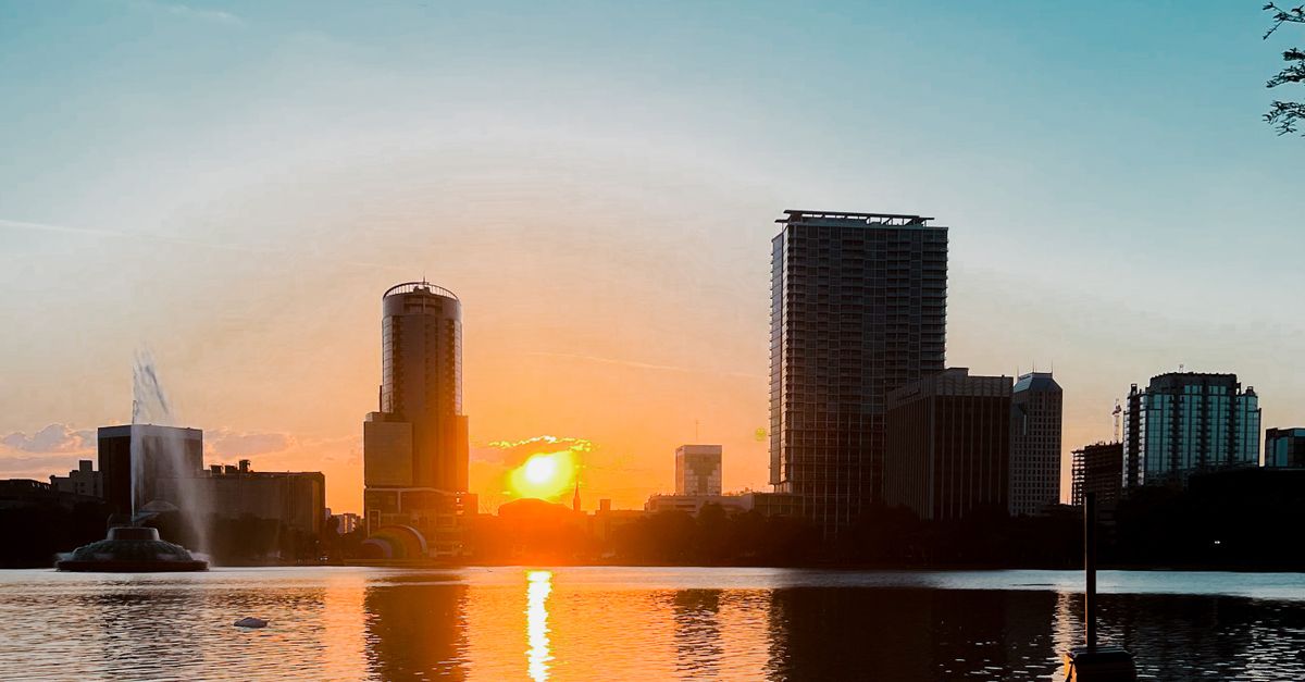 Stunning view of the Orlando skyline reflected in Lake Eola at sunset, capturing urban and natural beauty.