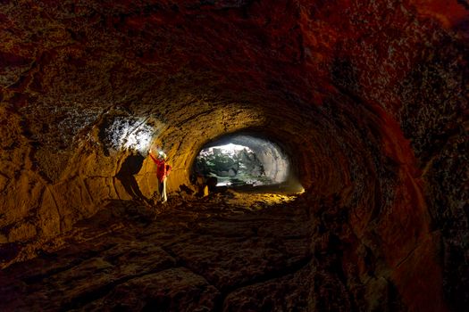 A person exploring a rugged cave with a flashlight, revealing textured walls.