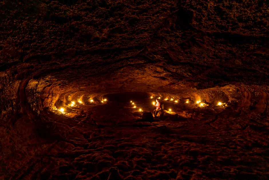 A person exploring a dimly lit cave with candles, showcasing natural rock formations.