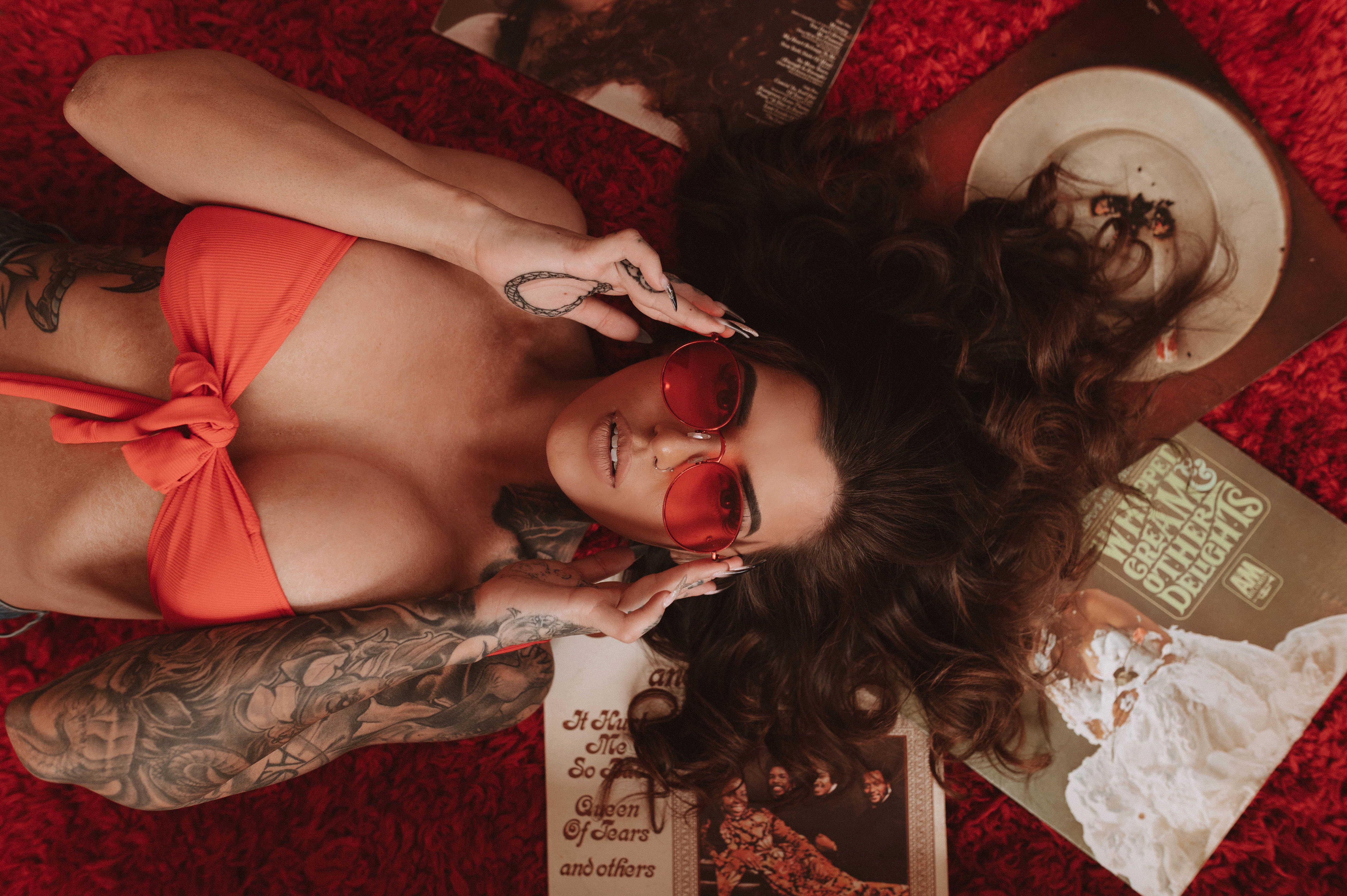 Fashionable woman on red carpet surrounded by vintage records wearing sunglasses.