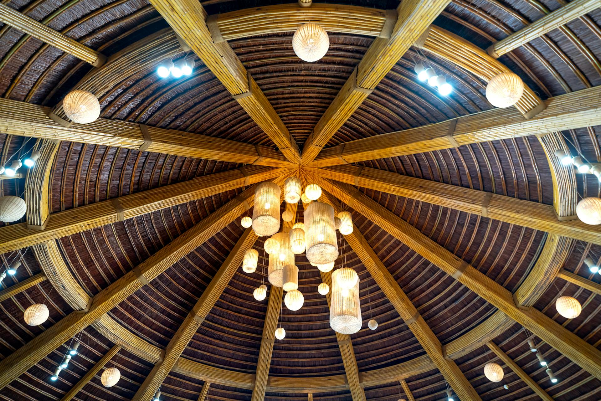 Captured from below, wooden beams and paper lanterns create a rustic dome interior.