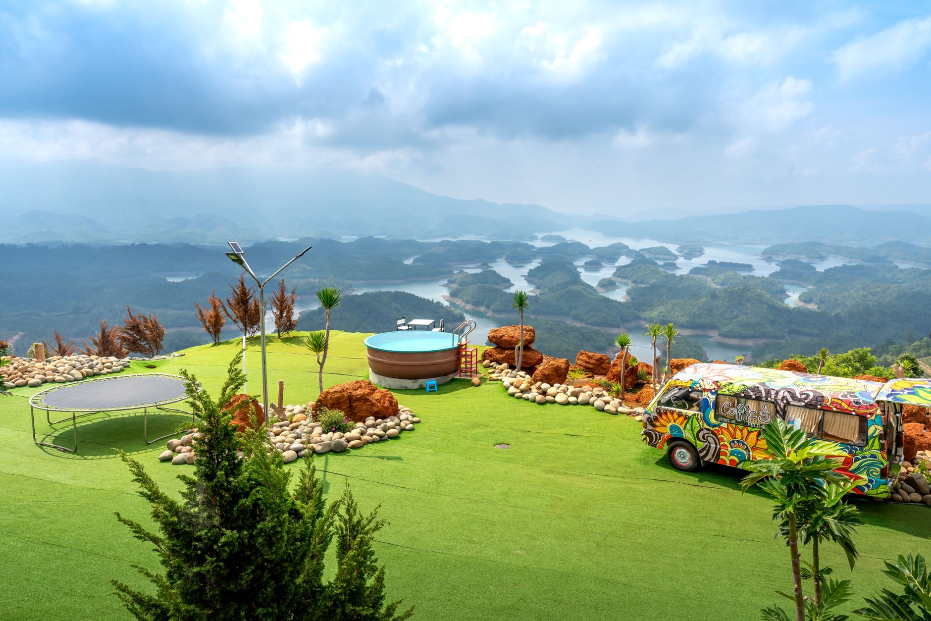 Colorful camper van and hot tub in a picturesque mountain landscape overlooking a serene lake.