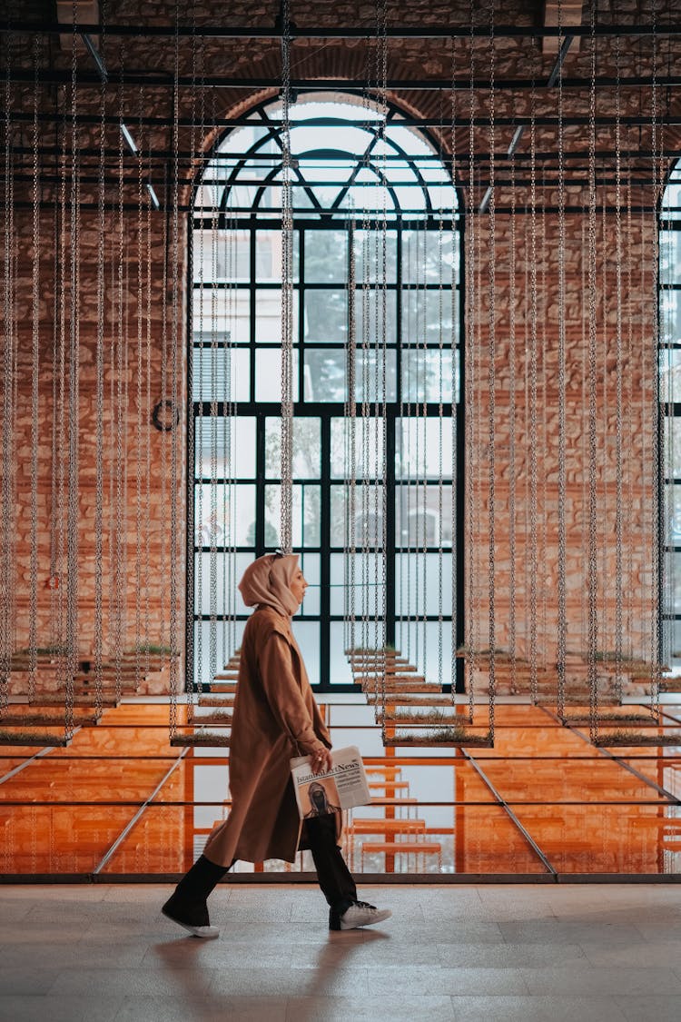 Woman In Hijab Walking By Swings In Building