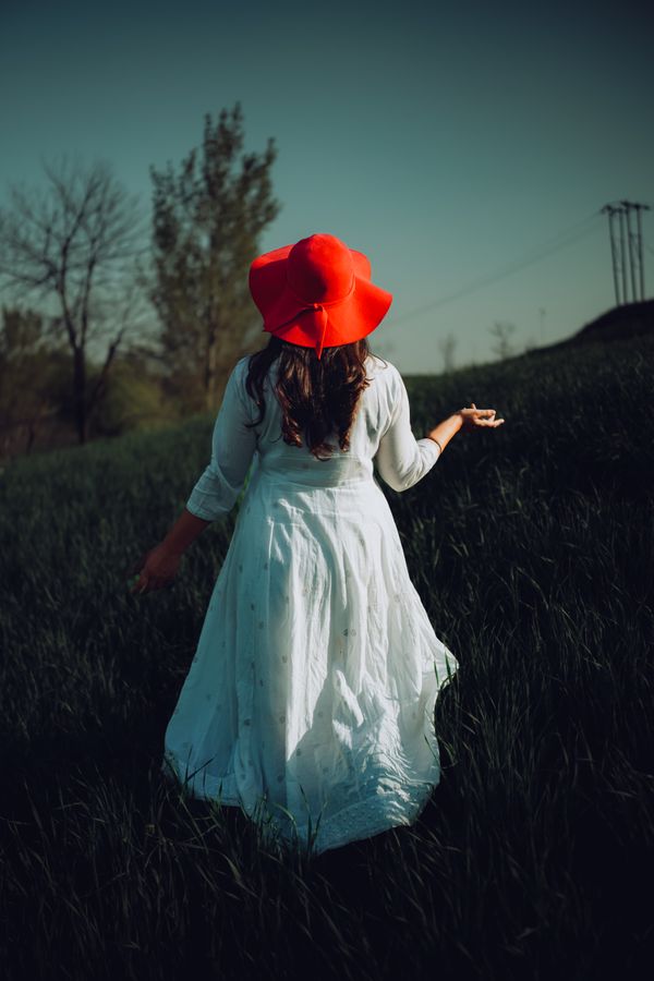 Woman in white dress and red hat looking at mountains in Kashmir