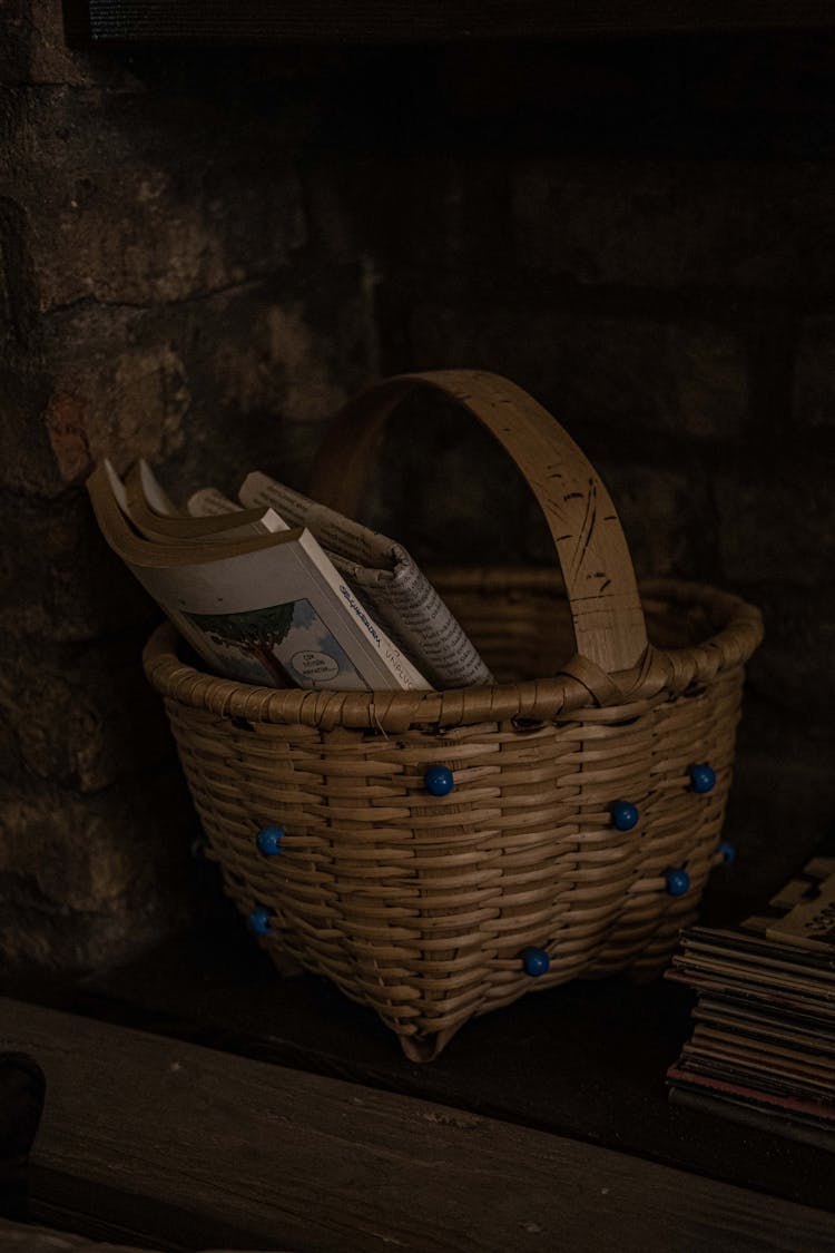 Old Books And Newspaper Inside Woven Basket