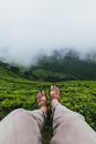 Person in Brown Pants and Black Flip Flops Sitting on Green Grass Field