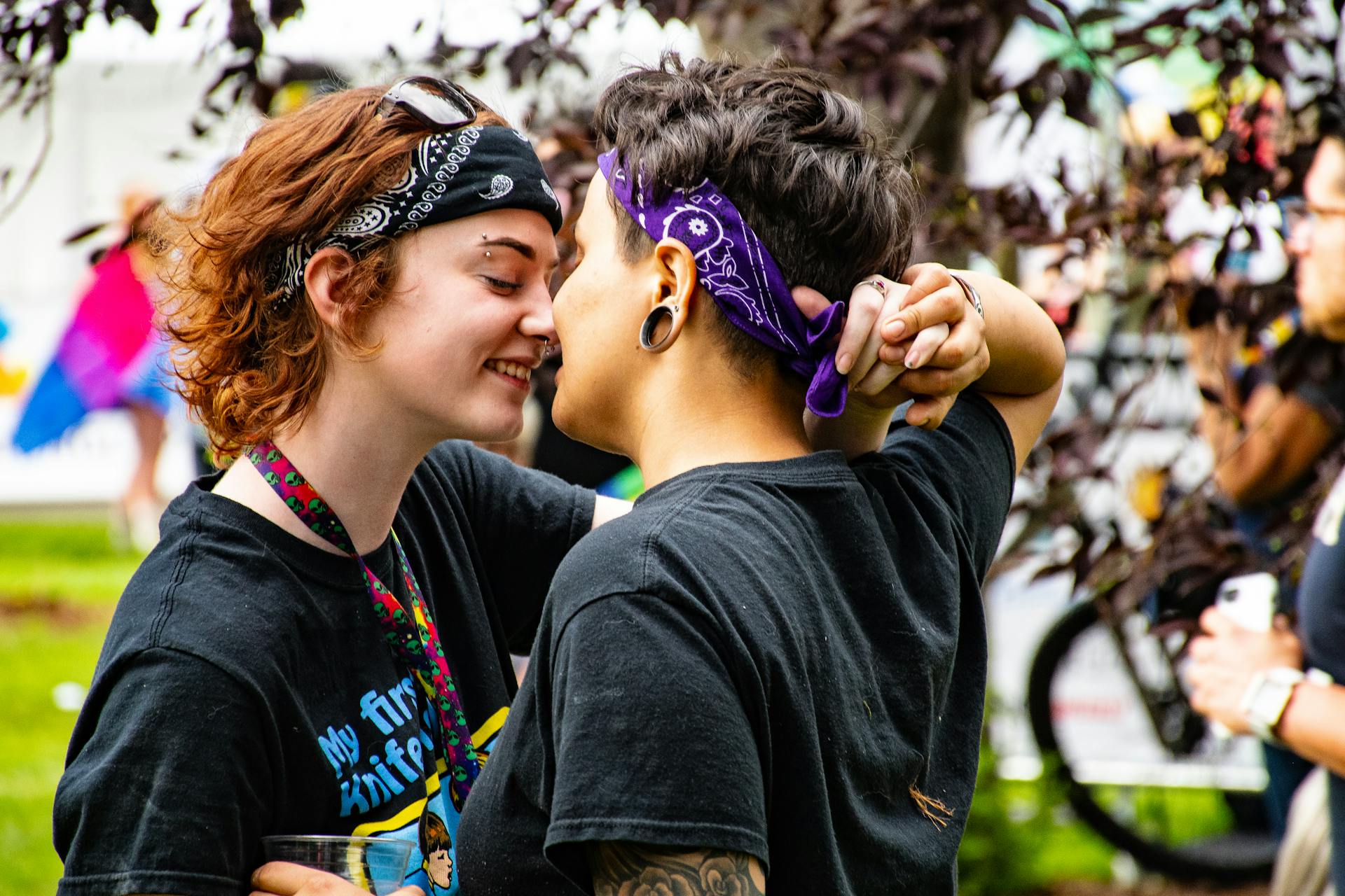 Two people embracing affectionately during a vibrant Pride celebration outdoors.