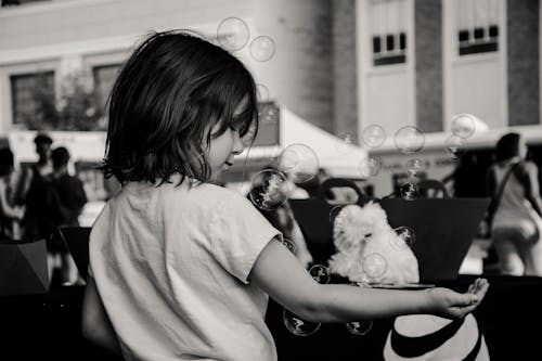 Monochrome Photography of Girl Playing With Bubbles
