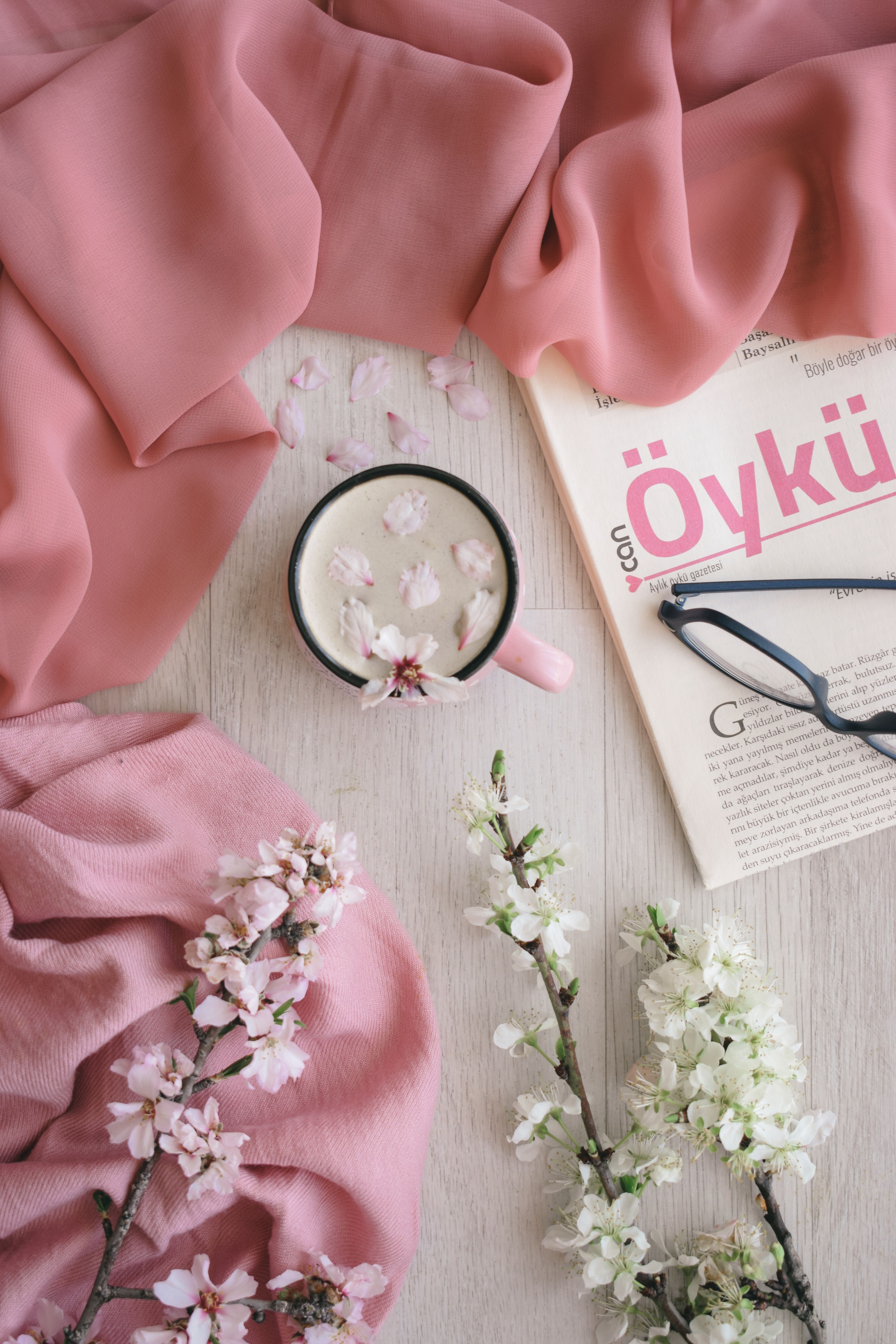 Chic flat lay of spring blossoms with a book and coffee, showcasing elegance.