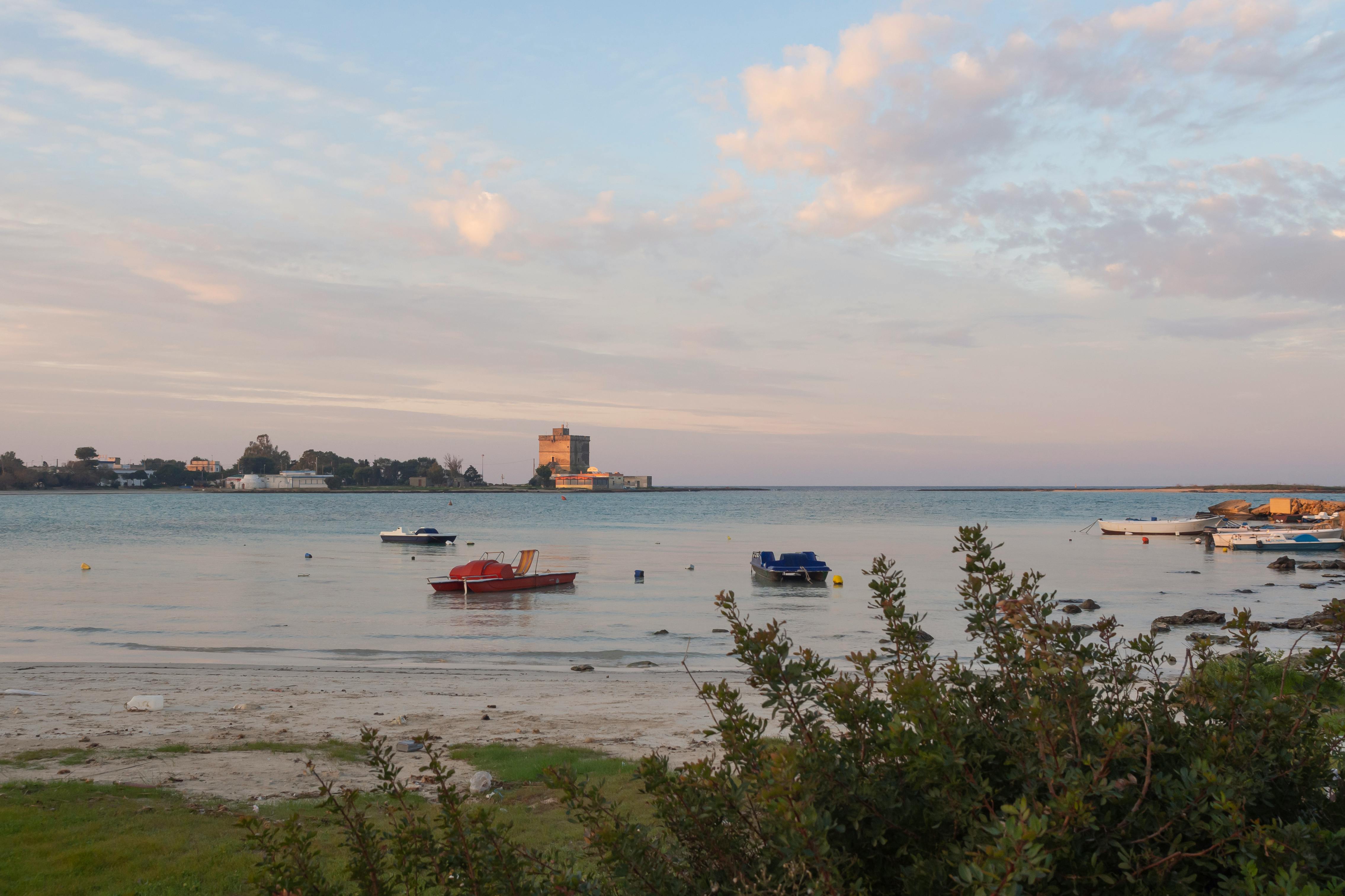 Serene view of boats on the calm waters near Nardò, Italy during sunset, capturing a peaceful coastal mood.