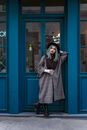 Woman in Gray Coat Standing Near Blue Door