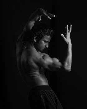 Muscular man posing shirtless in a studio with a dramatic flair.