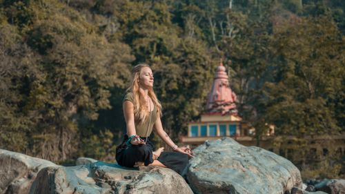Free A woman practices yoga on rocky terrain in Rishikesh, India, embracing peace and relaxation. Stock Photo