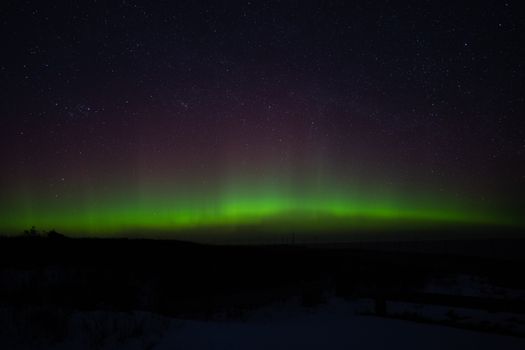 Mesmerizing northern lights displayed above Cavendish, PE, Canada, under a starry night sky.