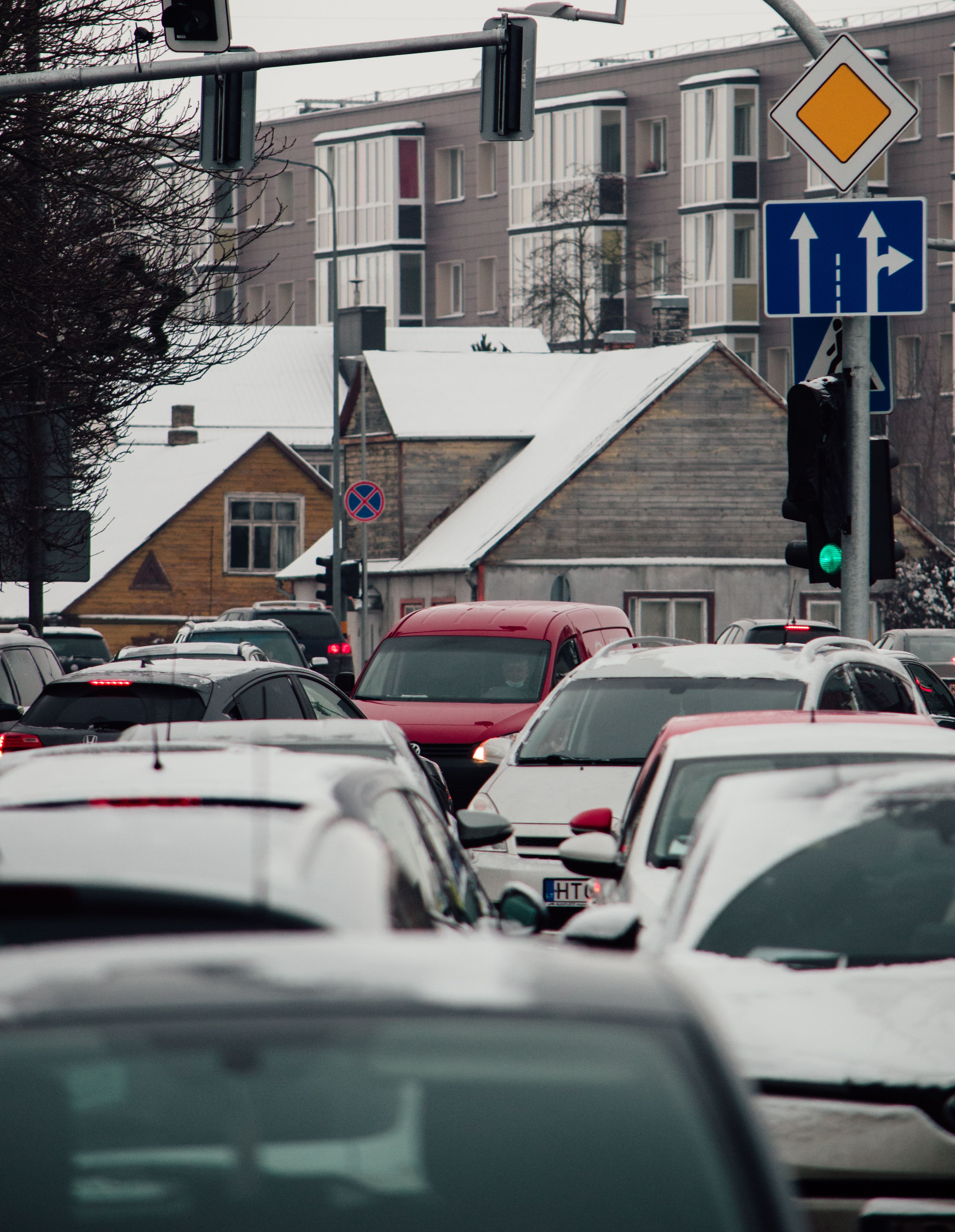 Snow-covered traffic jam in urban Lithuania, showcasing cars and city architecture during winter.