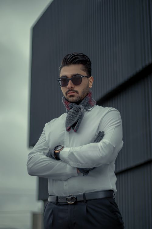 Free Confident young man in sunglasses posing with arms crossed outside an urban building. Stock Photo